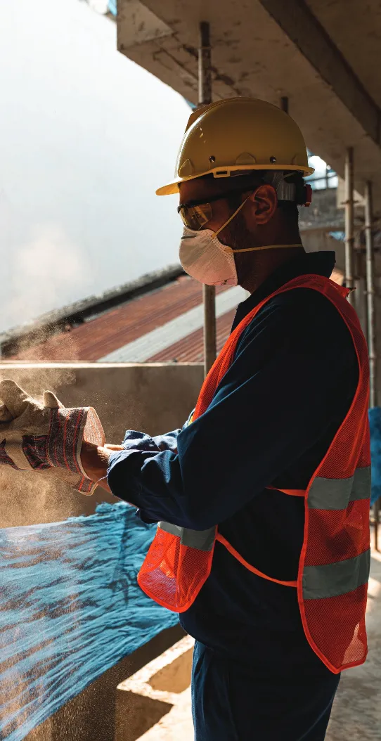 Site worker wearing a hard hat, dust mask and safety vest